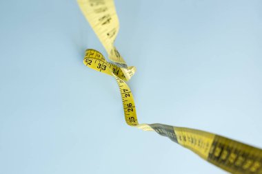 Terzi taksimetresi mavi arka planda asılı duruyor. Dikiş dikmek için mezura. Düz çizgi. Yakın plan..