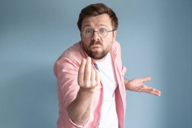 Adam para jesti yapıyor, parmaklarını ovuyor ve hiçbir şey ödemediğini dış görünüşüyle gösteriyor. İzole edilmiş, mavi arkaplan. 