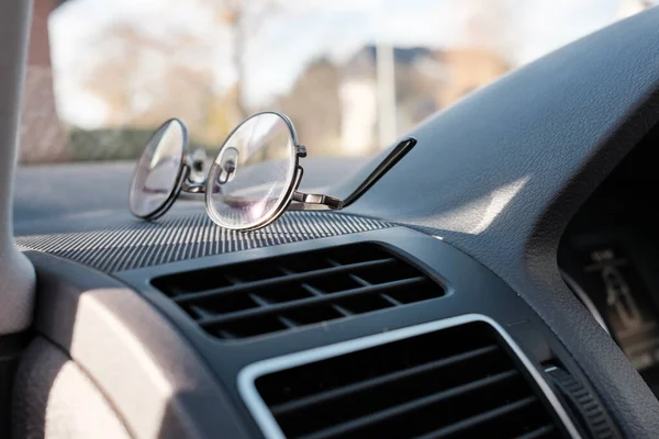 Glasses on the dashboard of a car.Essential accessory for drivers with vision problems. Concept of safe driving on the road. Close-up.
