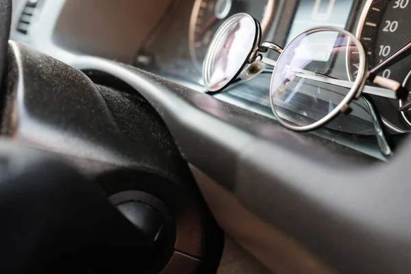 Glasses on the dashboard of a car.Essential accessory for drivers with vision problems. Concept of safe driving on the road. Close-up.