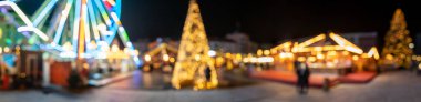 Noel pazarı. Güzel bulanık ve odağını kaybetmiş çelenk ışıkları, atlıkarınca ve köknar ağacı, bir lunaparkta, akşam vakti. Panorama.