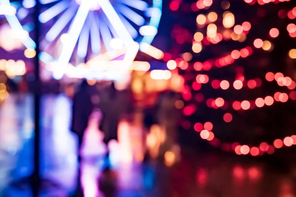 夜にカルーセルと装飾されたトウヒに美しくぼやけて焦点を当てた多色のガーランドライトを持つクリスマスマーケット — ストック写真
