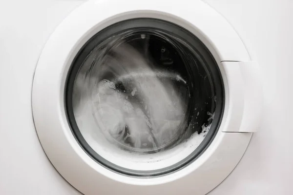 Washing machine with clothes inside. Laundry process. Close-up.