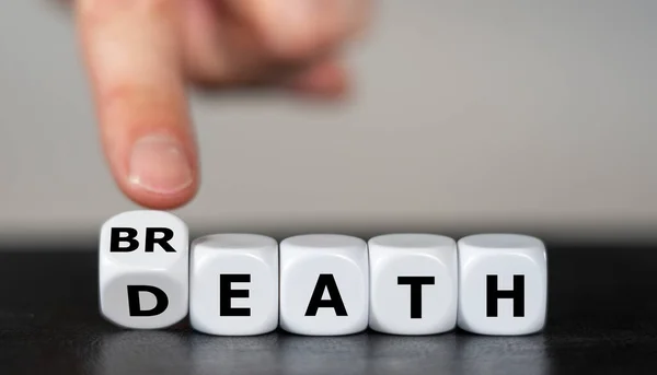 Hand turns dice and changes the word death to breath. Symbol for staying alive.