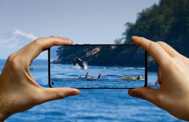 Orka sudan atlarken turist balina gezisinde cep telefonuyla fotoğraf çekiyor..