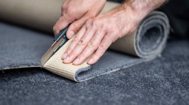 Handyman cutting a new carpet with a carpet cutter..	