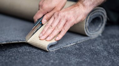 Handyman cutting a new carpet with a carpet cutter..	 clipart