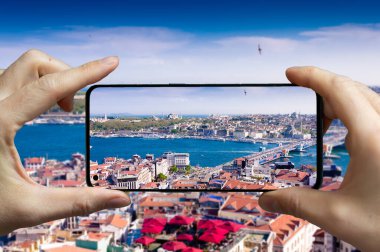 Türkiye 'nin İstanbul kentindeki Galata kulesinden cep telefonuyla fotoğraf çeken turist.