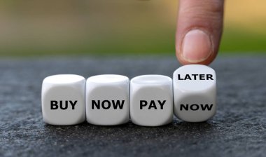 Hand turns dice and changes the expression 'buy now pay now' to 'buy now pay later'.