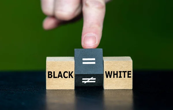 Symbol for equal rights of persons with different skin colors. Hand turns wooden cube and changes the unequal sign to a equal sign.