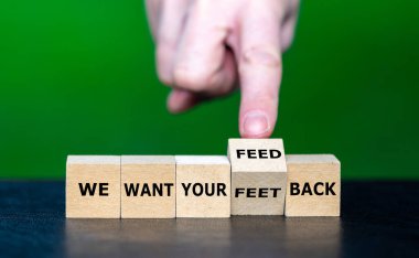 Hand turns wooden cube and corrects the funny slogan 'we want your feet back' to ' we want your feedback'.
