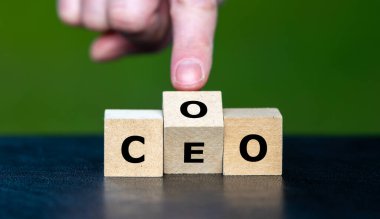 Hand turns cube and changes the abbreviation COO (chief operating officer) to  CEO (chief executive officer). clipart