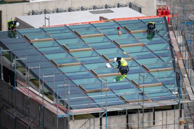 Roofer installing windows for a light well on the roof of a commercial building.	