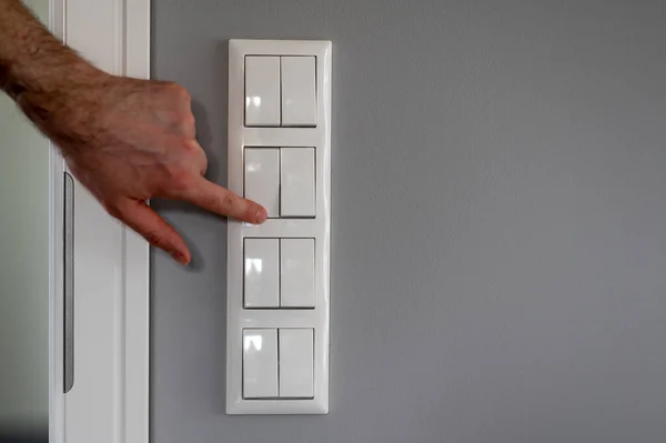 Row of eight light switches, while a finger switches on one light switch.