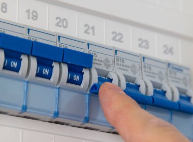 Teknisyen, özel bir evin sigorta kutusunda birden fazla sigorta düğmesi açıyor..