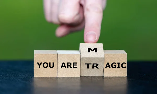 stock image Hand turns wooden cube and changes the expression ' you are tragic' to 'you are magic'.