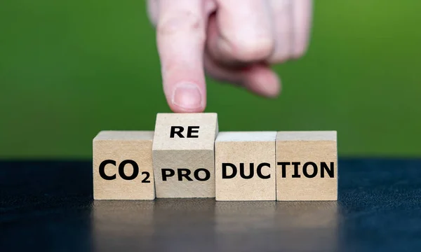 Hand turns wooden cube and changes the expression \'CO2 production\' to \'CO2 reduction\'.