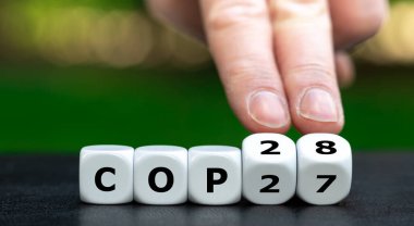 Bir sonraki iklim konferansının sembolü. El küpleri döndürür ve 'COP27' ifadesini 'COP28' olarak değiştirir.