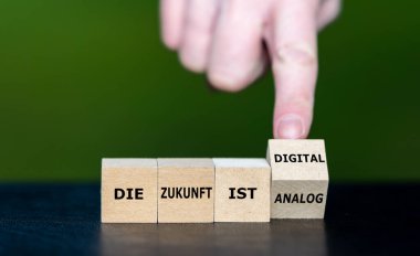 Symbol for a digital future. Hand turns wooden cubes and changes the German expression 'die Zunkunft ist analog' to 'die Zukunft ist digital' (the future is digital). clipart