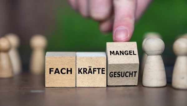 ハンドは木製の立方体を回し ドイツ語の表現を Fach Ukraineefteuhek Fach Ukraineeftemangel に変更する 熟練労働者が要求する ロイヤリティフリーのストック写真