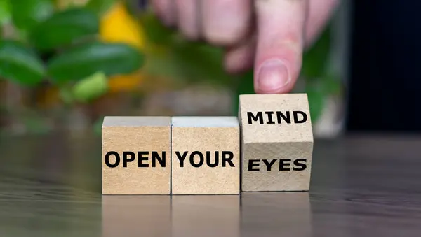 Hand turns cube and changes the expression \'open your eyes\' to \'open your mind\'.