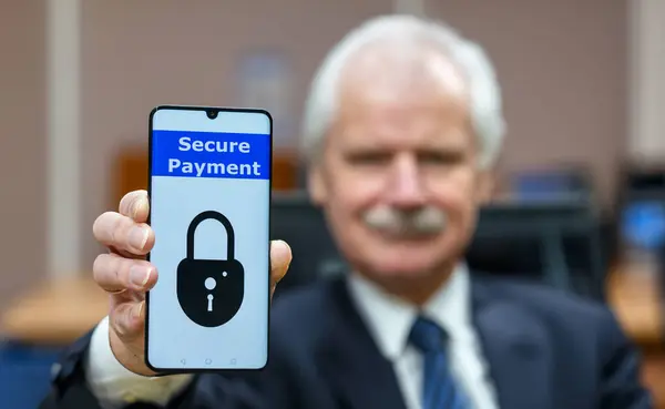 Elderly man holding a mobile phone with the text \'secure payment\'. Symbol for internet safety for elderly people.