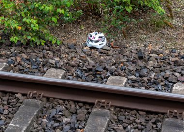 A child helmet next to train tracks. Symbol for an train accident. 	