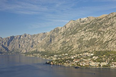 Karadağ 'ın tuhaf Kotor kasabası sakin körfez boyunca yuva kurarken, arka planda görkemli Balkan Dağları yükseliyor.