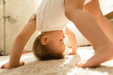 Mayo giyen sevimli, oyuncu küçük çocuk yatak odasında baş aşağı duruyor..
