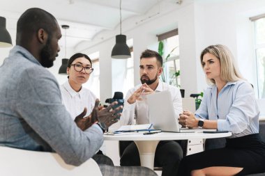 Modern ofiste yapılan toplantıda bir grup çok ırklı iş adamı