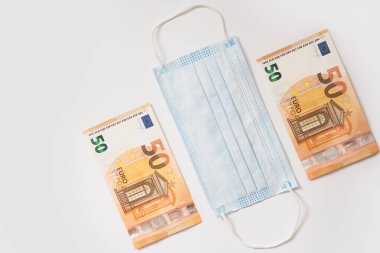 Hijyenik yüz maskesi ve 250 Euro 'luk banknotlar. Covid-19 'dan sonra ortaya çıkan mali kriz kavramı.