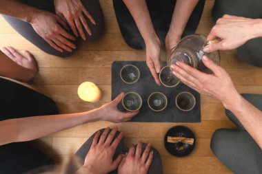 Genç bir kadın çay seremonisi sırasında tepsinin etrafında oturan arkadaşlarına sıcak çay dolduruyor..