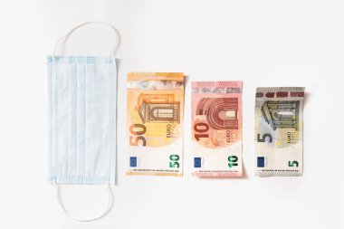 Tek kullanımlık hijyenik maske ve bar çizelgesini gösteren farklı değerde avro banknotları. Covid-19 'dan sonra ortaya çıkan mali kriz kavramı.