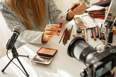 Ruj fırçası aplikatörüyle kadın ellerine yakın çekim. Kadın güzellik blogcusu kozmetik ürünlerinin video incelemesini yapıyor.