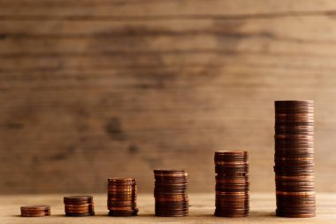 Çubuk grafiğini gösteren küçük, parlak bakır para yığınları. Finansal başarı ve kâr artışı kavramı.