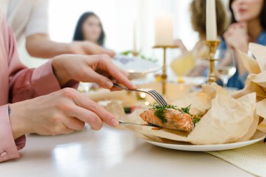 Kadın şenlik masasında bıçakla dereotu baharatlı kızarmış somon kesiyor..