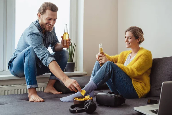 Junges Fröhliches Paar Sitzt Auf Dem Sofa Trinkt Bier Und — Stockfoto