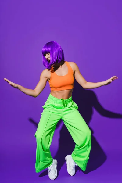 Беззаботная Активная Танцовщица Разноцветной Спортивной Одежде Веселится Фиолетовом Фоне — стоковое фото