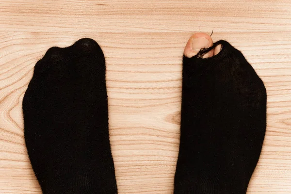 木製の床の背景に突き出たつま先で古い神聖な靴下に男性の足のクローズアップショット 貧困と金融危機の概念 — ストック写真