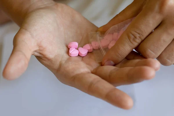 Zdjęcie Bliska Mężczyzny Wylewającego Różowe Tabletki Kształcie Serca Dłoń Przezroczystej — Zdjęcie stockowe