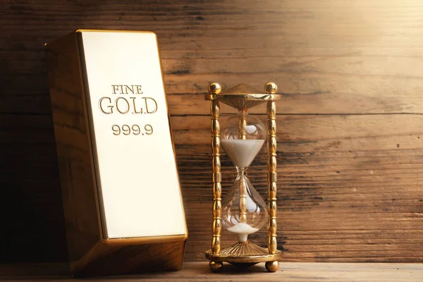 砂と重い光沢のある金のバーを注ぐと砂時計のクローズアップショット 貨幣価値の概念 — ストック写真