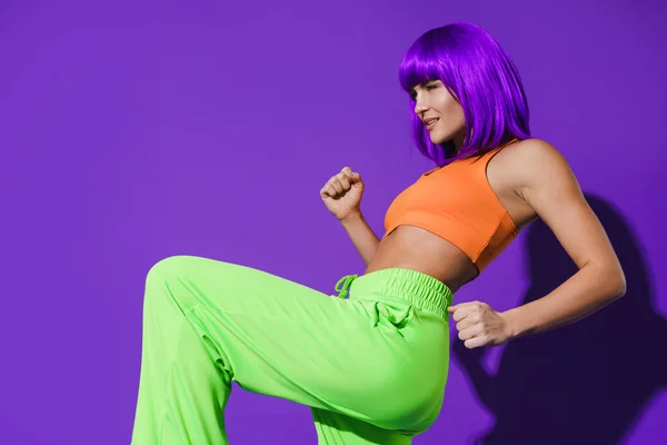 Беззаботная Активная Танцовщица Разноцветной Спортивной Одежде Веселится Фиолетовом Фоне — стоковое фото
