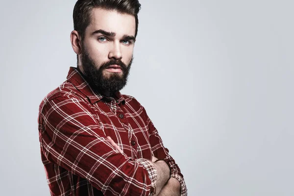 灰色の背景にチェッカーシャツを着たハンサムな髭の男の肖像 — ストック写真