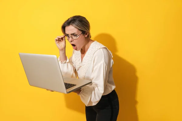 Sarı Arka Planda Dizüstü Bilgisayar Kullanan Gözlüklü Genç Bir Kadın — Stok fotoğraf