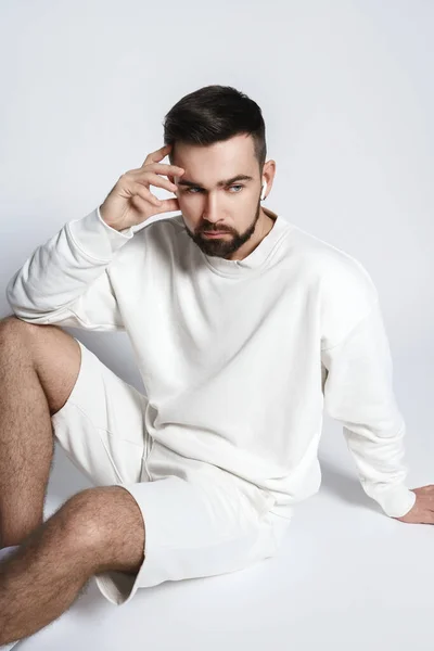 Handsome Man Wearing White Sweatshirt Shorts Wireless Earbuds Sitting Gray — Stock Photo, Image