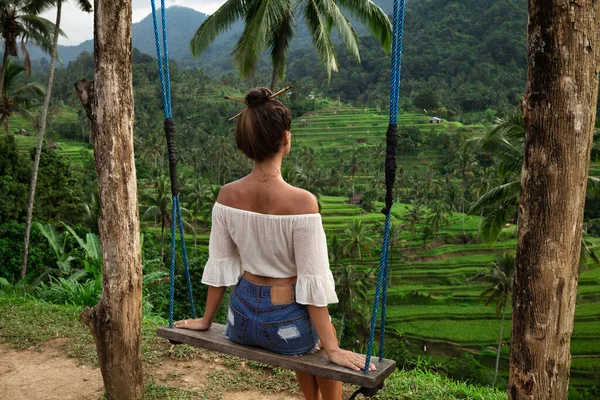 Young woman on rope swings with beautiful view on rice terraces in the Bali.