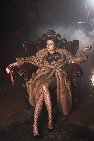 Provocative image of gorgeous woman wearing fur coat and holding piece of raw beef. Animal rights concept.