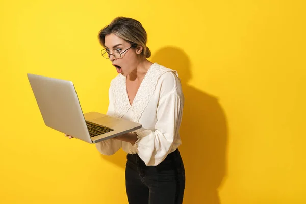 Młoda Zaskoczona Kobieta Nosząca Okulary Pomocą Laptopa Żółtym Tle — Zdjęcie stockowe