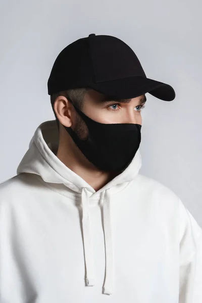 Junger Mann Mit Weißem Kapuzenpulli Schwarzer Baseballkappe Und Stoffgesichtsmaske Vor — Stockfoto
