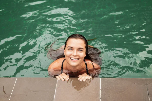 在游泳池里放松的笑容满面的年轻女子的画像 — 图库照片